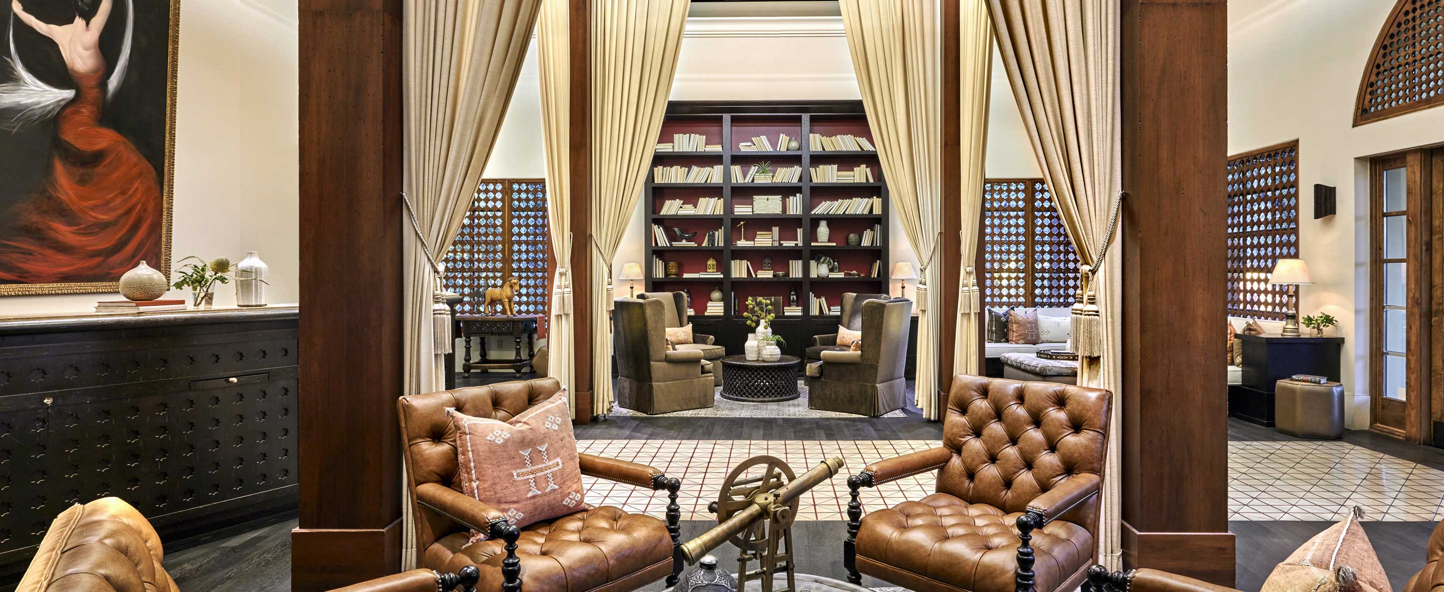 Elegant interior lounge with leather seating, bookshelves, and draped windows