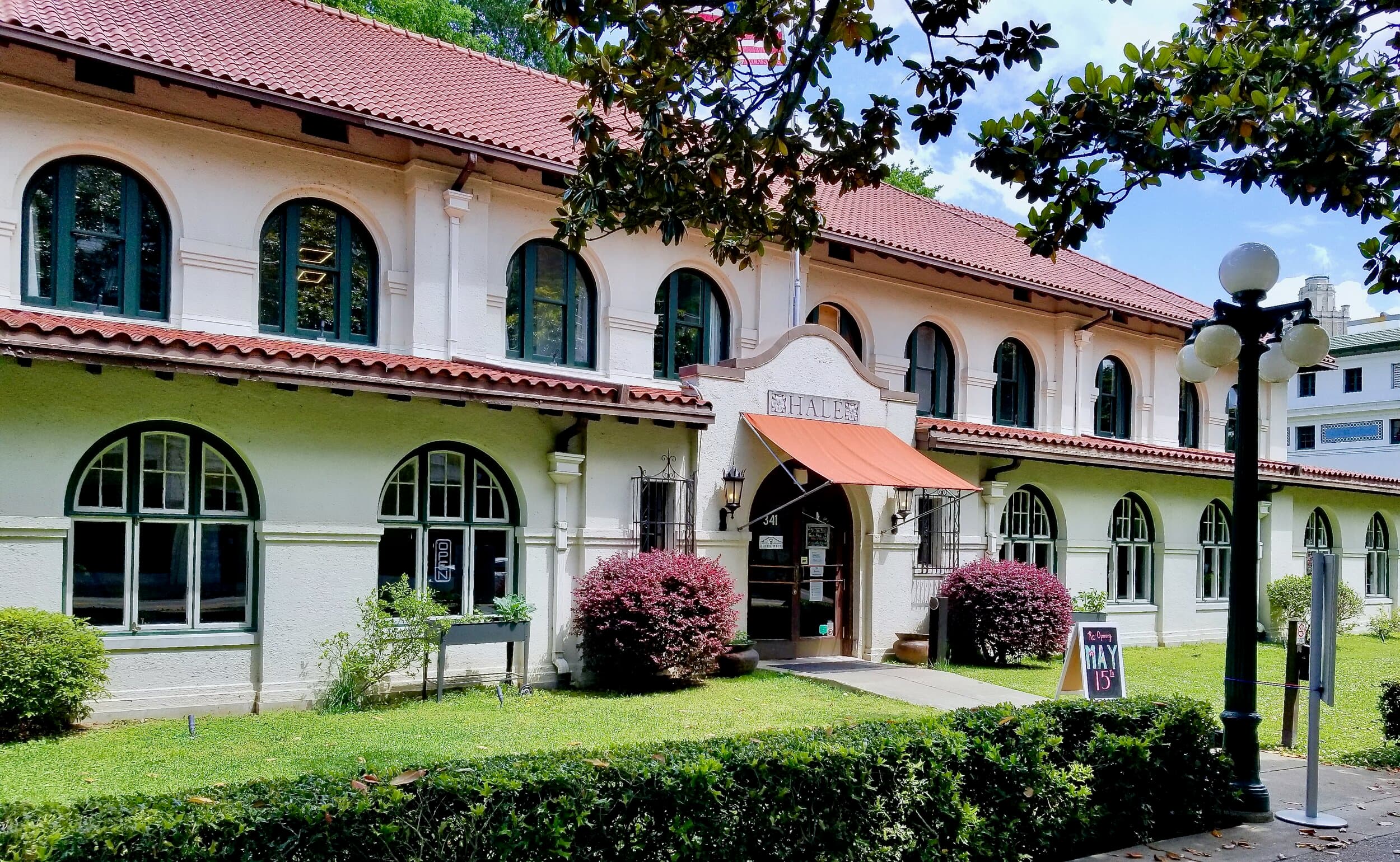 Colonial-style hotel building with white facade, terracotta roof, arched windows, and manicured grounds