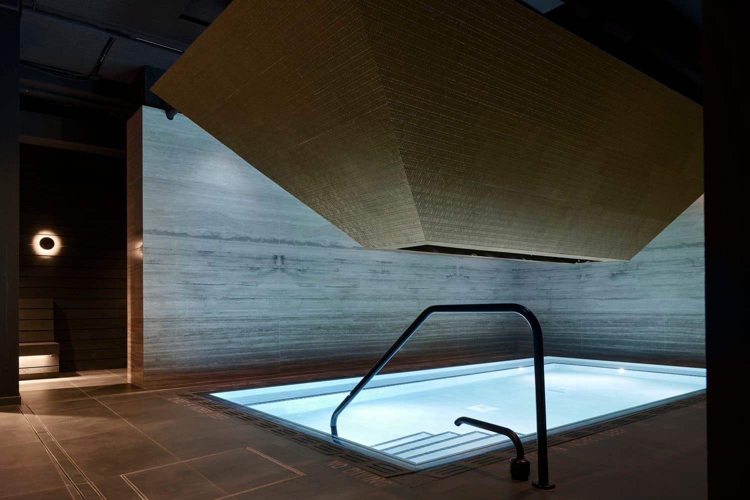 Modern spa bath chamber with geometric ceiling and illuminated water basin