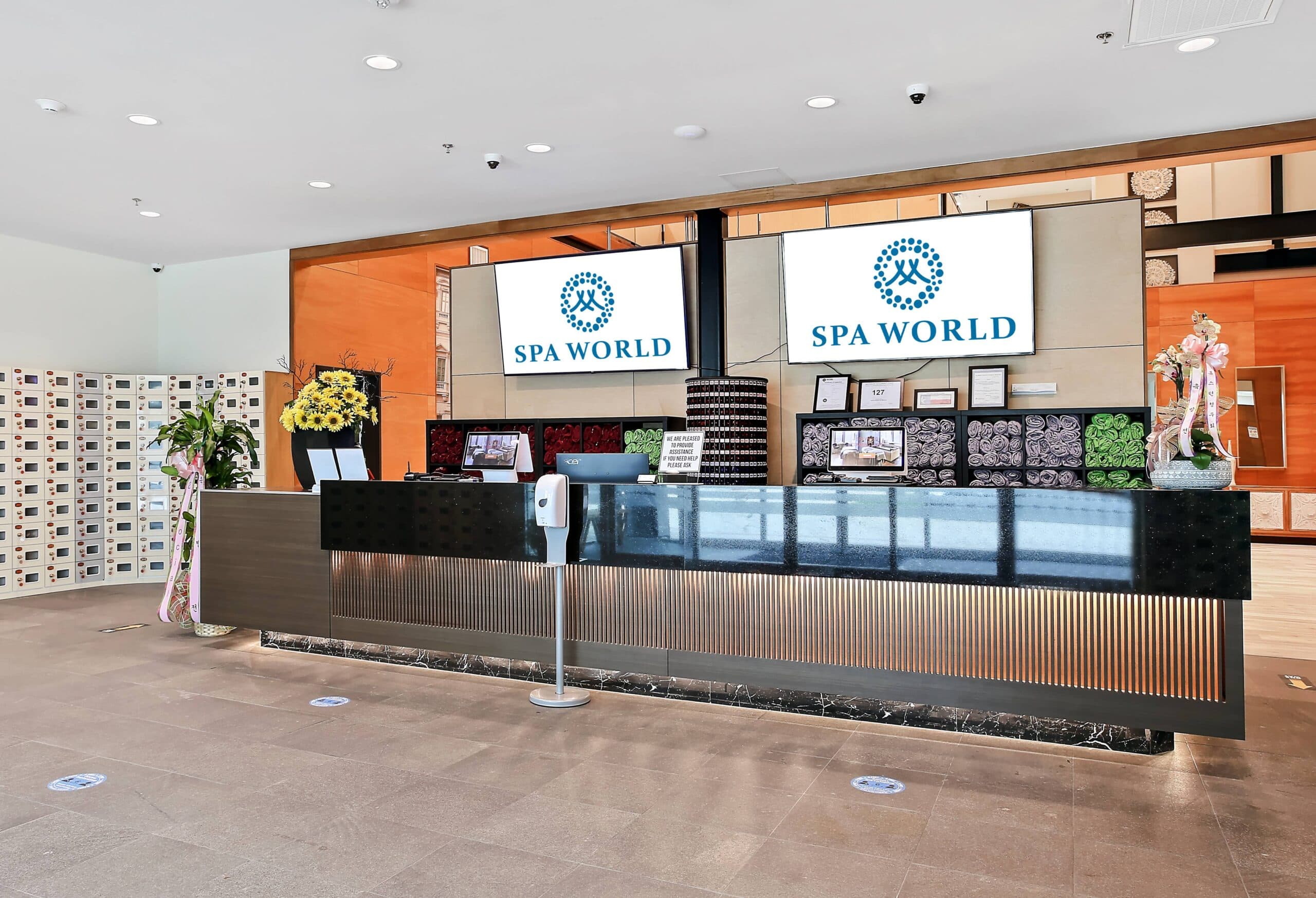 Modern spa reception desk with orange accent walls and Spa World branding signage