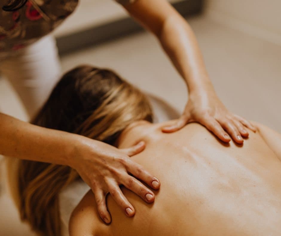 Therapist performing back massage on client in treatment room