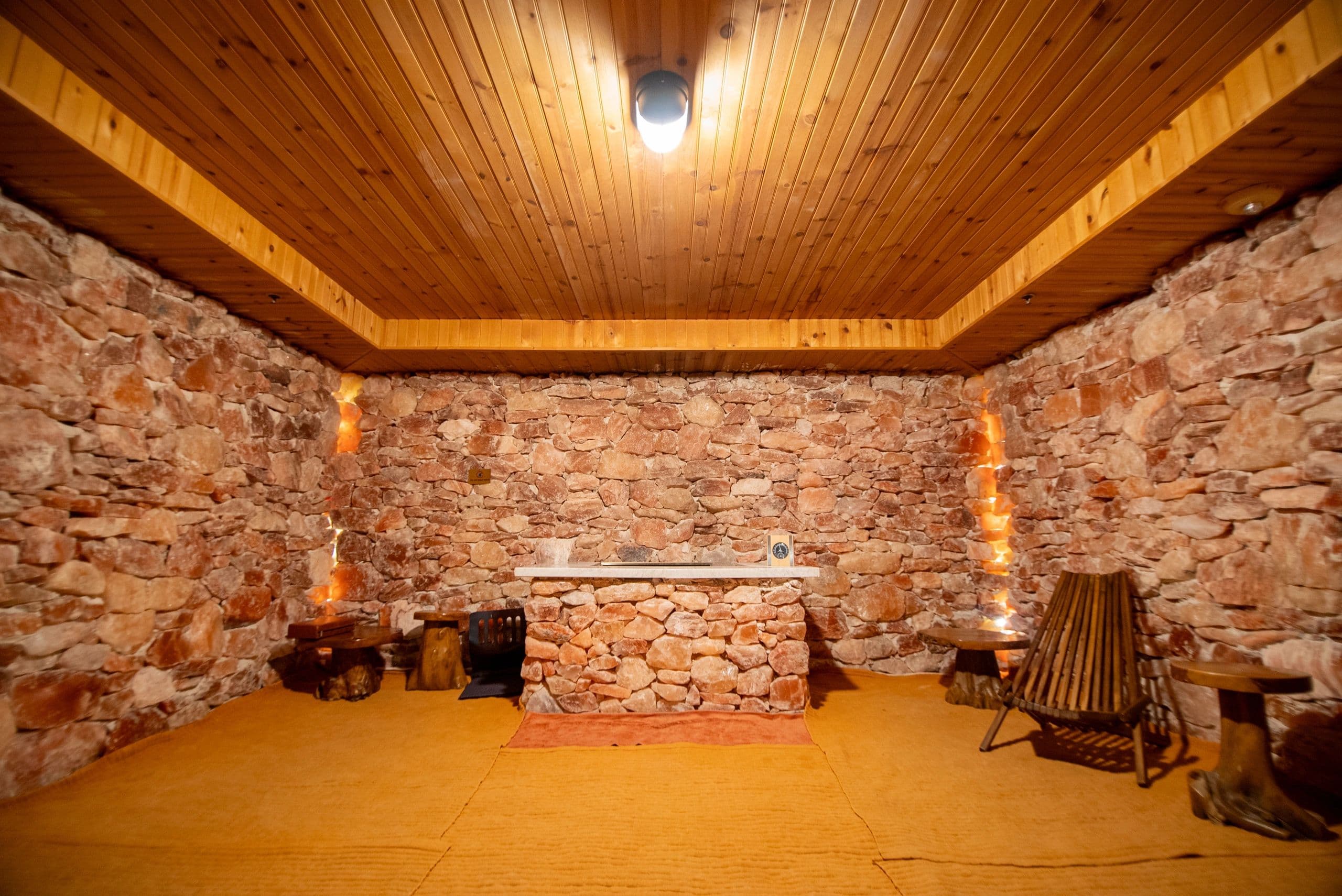 Salt therapy room with wooden ceiling, stone walls, and ambient lighting