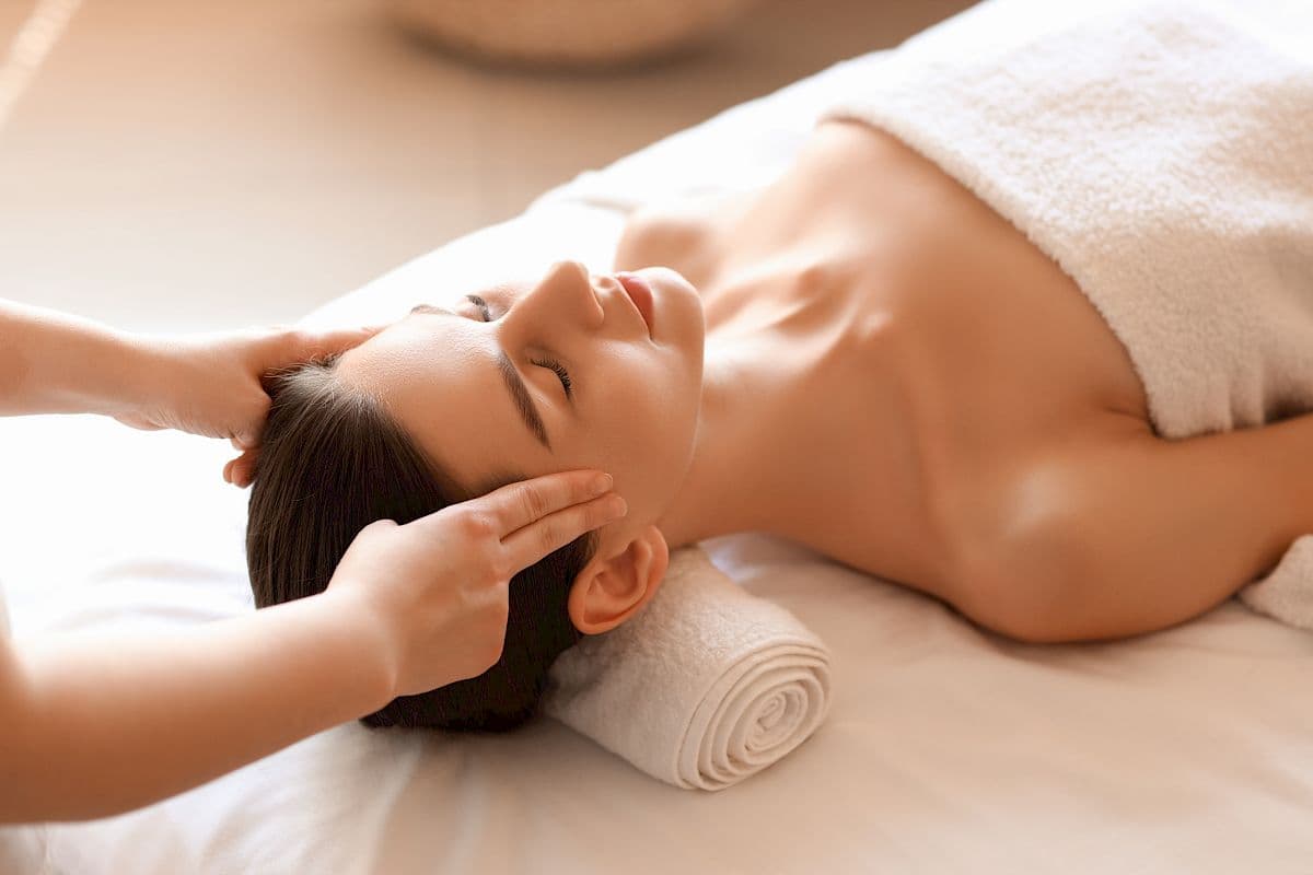 Person receiving a head and neck massage treatment with therapist's hands