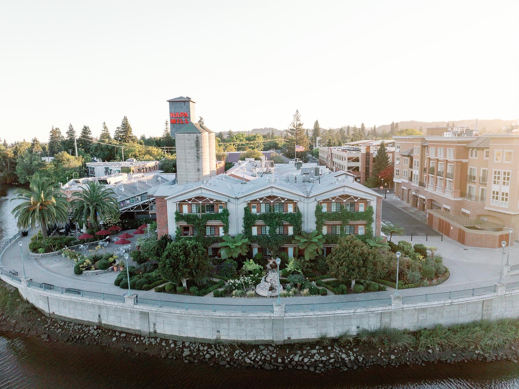 Aerial view of The Spa at Napa River Inn with ivy-covered building, courtyard, and waterfront setting surrounded by trees