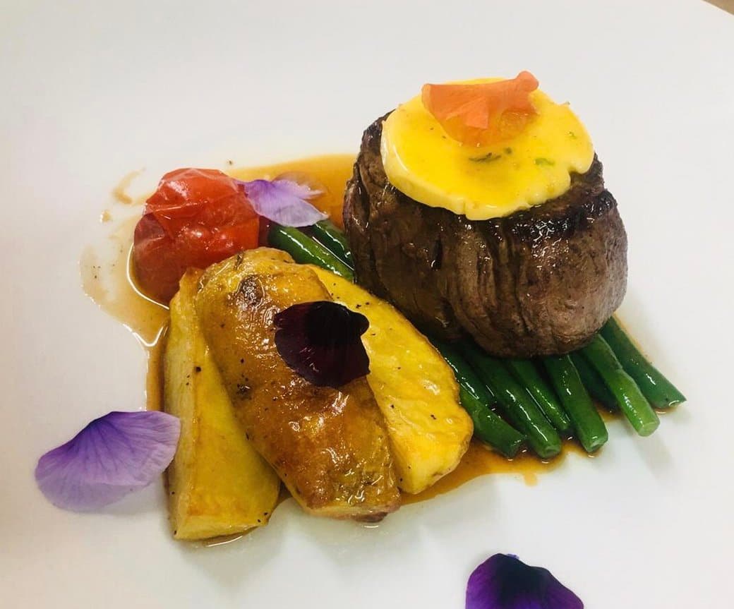 Plated fine dining dish with steak, foie gras, asparagus and edible flowers