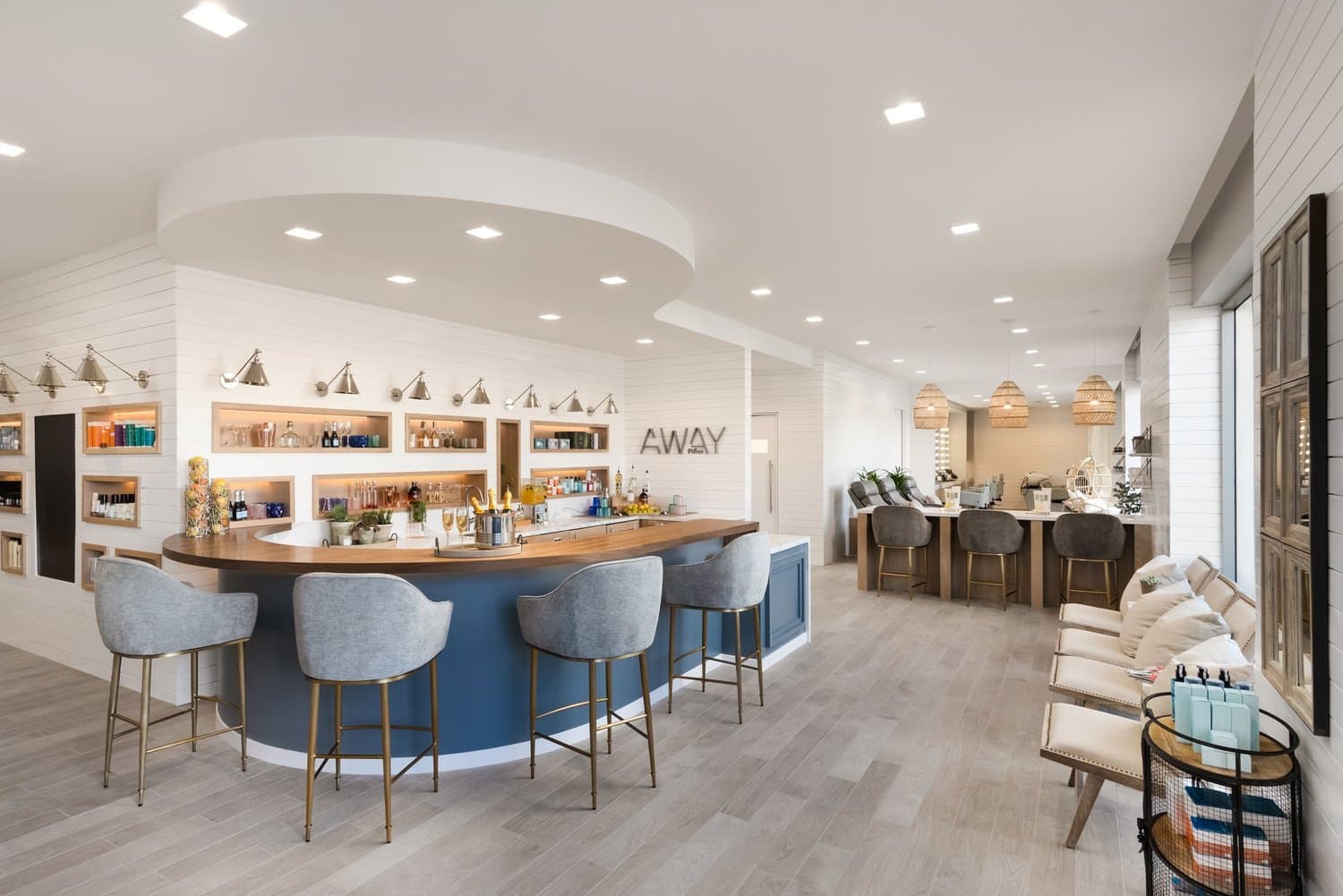 Modern spa reception area with curved blue desk, white shelving, and ambient lighting